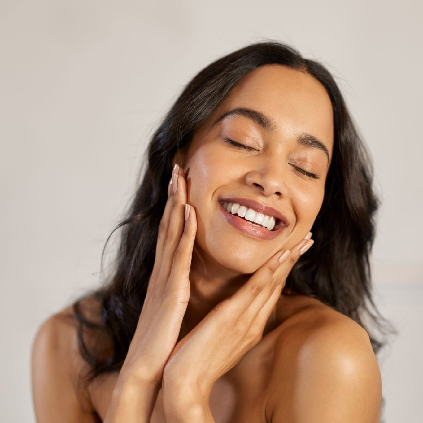 A smiling woman with curly hair and clear, smooth skin after electrolysis at Body Hair Gone